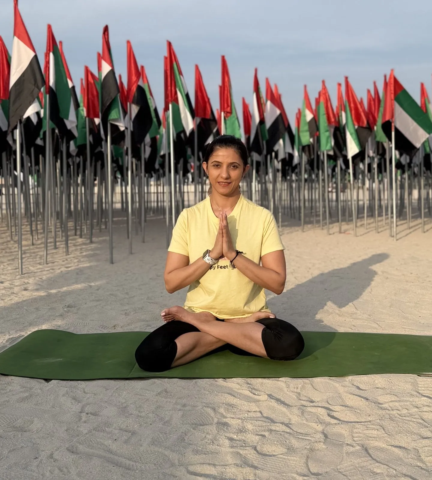 Seated in meditation on a mat at the beach, hands at the heart