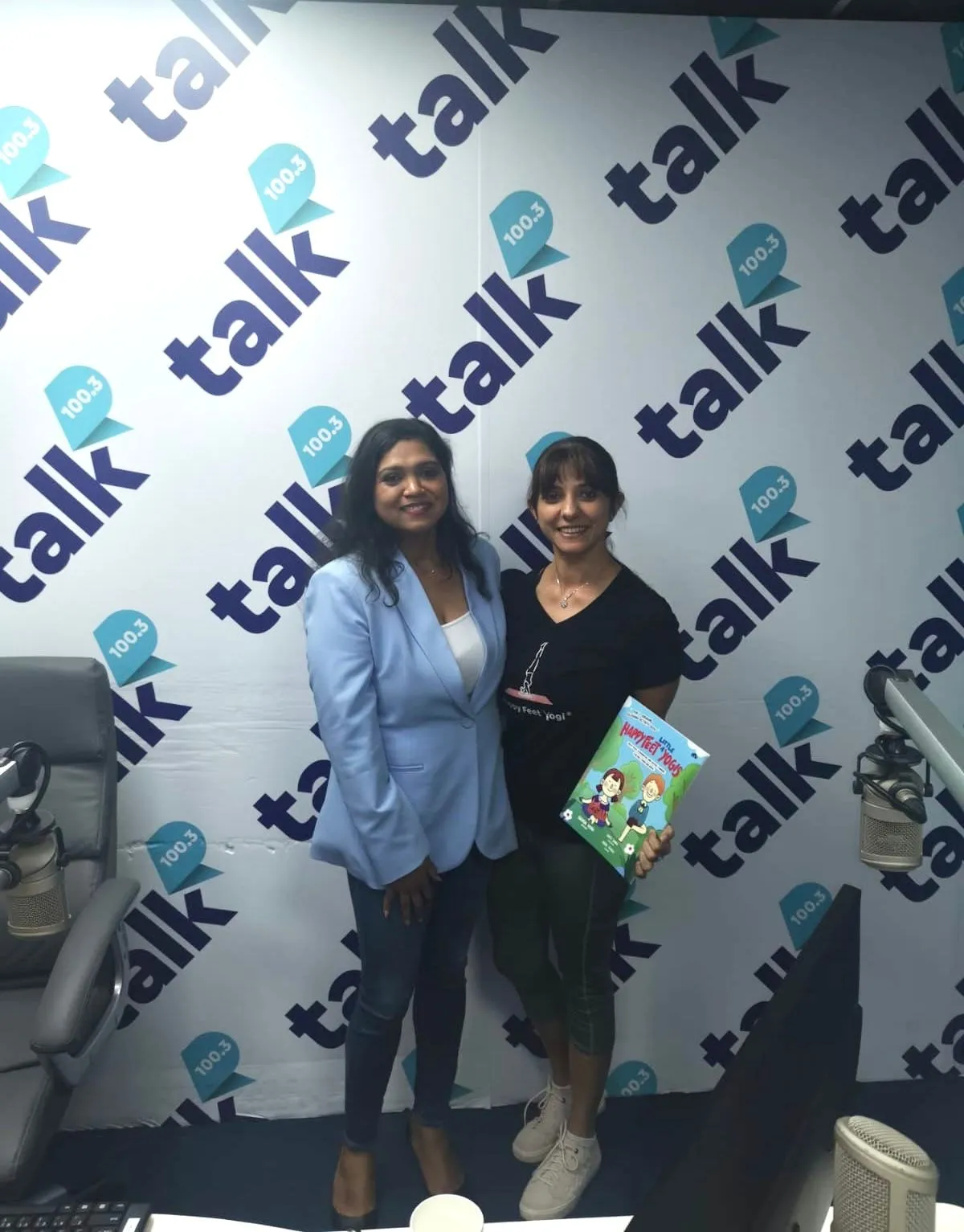 Brinda with the show's host in the Talk 100.3 FM studio, holding Happy Feet ‘Little’ Yogis